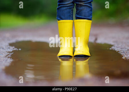 Kind tragen regen Stiefel in einer Pfütze steht auf warmen Sommertag Stockfoto