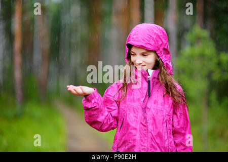 Adorable kleine Mädchen glücklich spielen im Regen auf warmen Sommertag Stockfoto