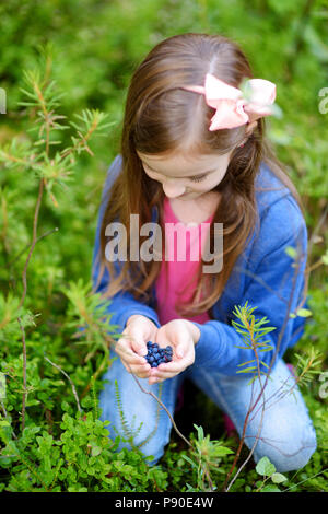 Süße kleine Mädchen pflücken Heidelbeeren in den Wäldern auf schönen Sommertag Stockfoto