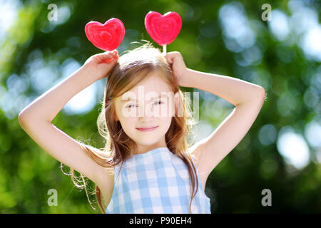 Süße kleine Mädchen mit großen herzförmigen Lutscher im Freien auf schönen Sommertag Stockfoto