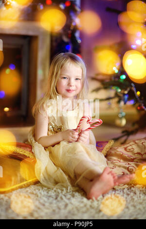Weihnachten Portrait von glücklichen kleinen Mädchens durch einen Kamin in der gemütlichen dunklen Wohnzimmer auf Heiligabend Stockfoto