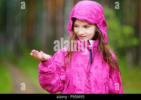 Adorable kleine Mädchen glücklich spielen im Regen auf warmen Sommertag Stockfoto