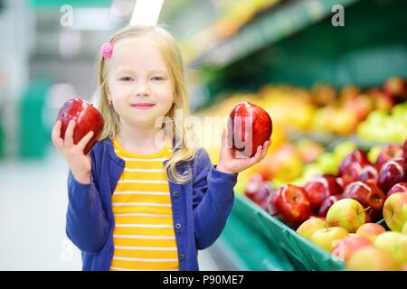 Kleines Mädchen Auswahl reife Äpfel in einem Kaufhaus oder Supermarkt Stockfoto