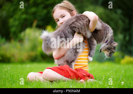 Süße kleine Mädchen, dass riesige Katze im Freien auf schönen Sommertag Stockfoto