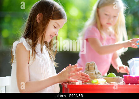 Zwei süße kleine Mädchen spielen mit kinetischen Sand an sonnigen Sommertag im Freien Stockfoto