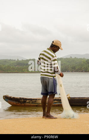 Fischer falten Fischernetz am Ende des Tages auf Cavelossim Beach, Cavelossim, Goa, Indien Stockfoto