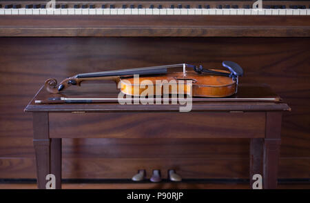 Vintage Violine und Bogen Festlegung auf der Werkbank mit Klavier im Hintergrund Stockfoto