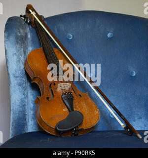 Vintage Violine und Bogen Auf blaue Taste getuftete Stuhl Stockfoto