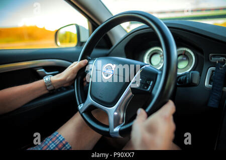 BERLIN/Deutschland - VOM 29. APRIL 2018: Fahrer in Shorts hält einen Volvo Lenkrad während der Fahrt mit dem Auto auf der Autobahn. Stockfoto