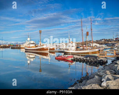 13. April 2018: Husavik, Island. Der Hafen in Husavik im Norden Island, mit Booten, darunter whale-watching Schiffe, die sich in den ruhigen Wasser spiegelt Stockfoto