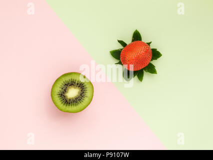 Eine Kiwi und eine halbe Erdbeere auf Duo Farbe Hintergrund Stockfoto