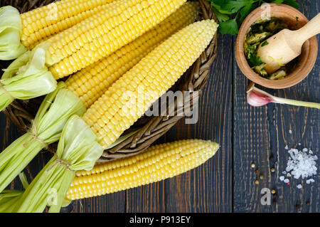 Rohzucker Mais, Meersalz, Gewürze, Kräuter, Butter auf einem dunklen Holztisch. Ansicht von oben. Stockfoto