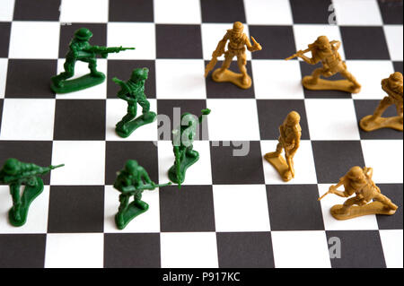 Zwei Armeen aus Kunststoff Spielzeug Soldaten einander gegenüber auf einem Schachbrett Stockfoto