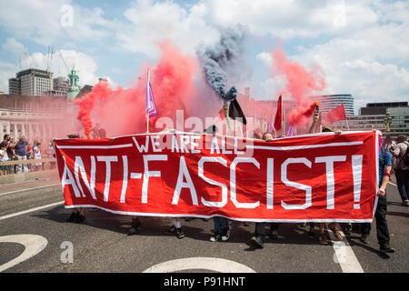 London, Großbritannien. 14. Juli 2018. Antifaschisten halten Rauch Granaten wie Sie März über die Westminster Bridge der rechtsextremen "Freien Tommy' (Robinson) und Trump Anhänger '' Willkommen Märsche Trump' zu erheben. Es gab einige Auseinandersetzungen, wie die anti-faschistischen März wurde von Freien Tommy Anhänger am Rande des Parliament Square angegriffen. Credit: Mark Kerrison/Alamy leben Nachrichten Stockfoto