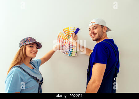 Nettes junges Paar lächelt, während sie Farbe Guide im Wohnzimmer Stockfoto