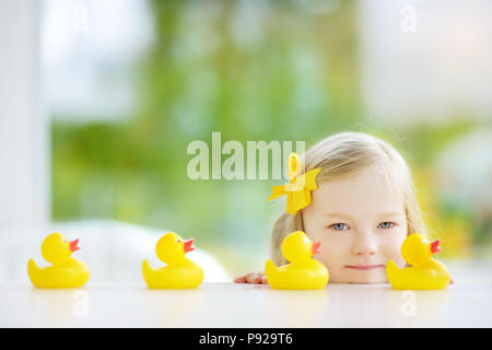 Süße kleine Mädchen spielen mit Gummi Entenküken zu Hause. Hübsches Kind Spaß mit Spielzeug Enten. Stockfoto