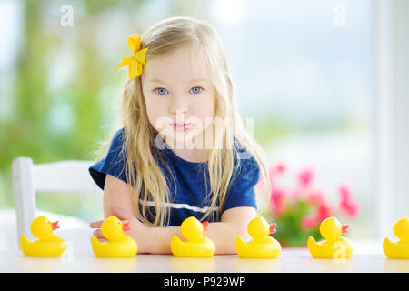 Süße kleine Mädchen spielen mit Gummi Entenküken zu Hause. Hübsches Kind Spaß mit Spielzeug Enten. Stockfoto