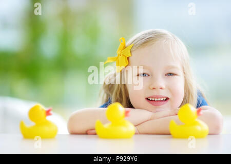 Süße kleine Mädchen spielen mit Gummi Entenküken zu Hause. Hübsches Kind Spaß mit Spielzeug Enten. Stockfoto