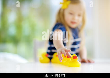 Süße kleine Mädchen spielen mit Gummi Entenküken zu Hause. Hübsches Kind Spaß mit Spielzeug Enten. Stockfoto