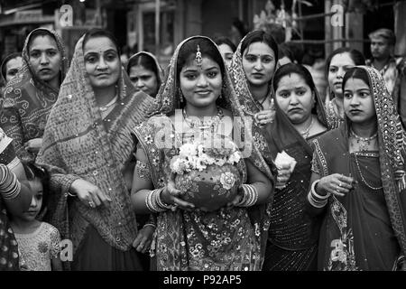 Rajasthani Frauen tragen ein irdenes Gefäß durch die Stadt als Teil der GANGUR JOHDPUR-Festival in Rajasthan, Indien Stockfoto