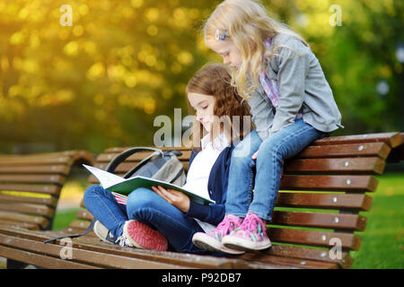 Adorable kleine Schülerinnen studieren im Freien auf hellen Herbst Tag. Junge Studierende ihre Hausaufgaben gemacht. Bildung für kleine Kinder. Zurück zu Konz Schule Stockfoto