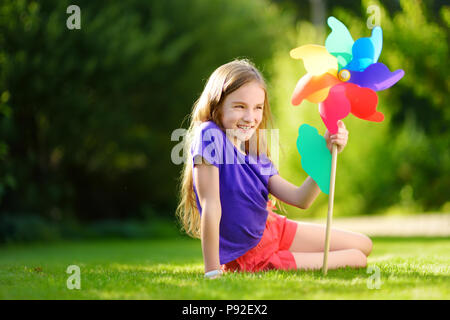 Adorable kleine Mädchen mit bunten Spielzeug pinwheel an warmen und sonnigen Sommer Tag Stockfoto