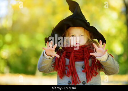 Adorable kleine Mädchen mit halloween kostüm Spaß auf einem kürbisfeld auf schönen Herbsttag. Glückliches Kind spielen im Herbst Park. Herbst activ Stockfoto