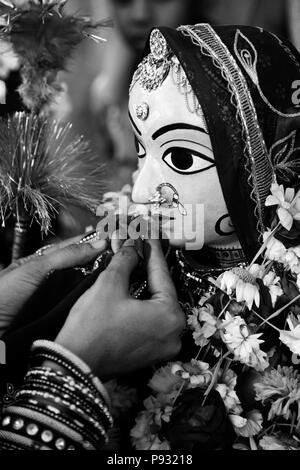 Ein Rajasthani Frau macht eine Blume offerting zu Shiva's Frau PARVATI am GANGUR FESTIVAL auch als der MEWAR FESTIVAL in Udaipur, Rajasthan, IN bekannten Stockfoto