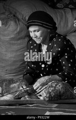 Eine Fishermans' Frau Reparaturen einem Fischernetz im Dorf Tung Nang Dam in der Andamanensee - Thailand Stockfoto