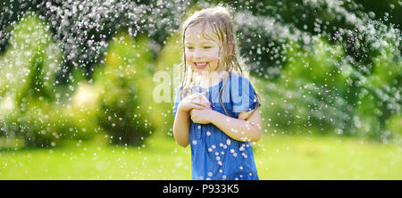 Adorable kleine Mädchen spielen mit einem Sprinkler in einem Hinterhof an sonnigen Sommertag. Niedliche Kind Spaß mit Wasser im Freien. Lustige Spiele für kid Stockfoto