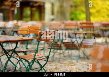 Leeren Café im Freien auf der schönen Herbsttag in München, Deutschland. Leere chiars und Tabellen unter Kastanien im Herbst Saison. Stockfoto