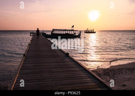 Man Walking am Pier bei Sonnenuntergang auf den Malediven Island Resort Stockfoto