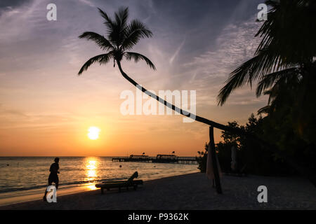 Frau Laufen am Strand bei Sonnenuntergang auf den Malediven Island Resort Stockfoto