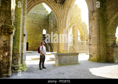 Männliche Tourist in Jerpoint Abbey, eine zerstörte Zisterzienserabtei, in der zweiten Hälfte des 12. Jahrhunderts gegründet, in der Nähe von Thomastown, County Kilkenny, ICH Stockfoto