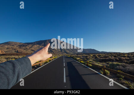 Gerade asphaltierte Straße mit Finger, zeigt die Spitze des Pico del Teide Vulkan im Hintergrund. Nationalpark Teide, Teneriffa, Kanarische Inseln, Spanien. Stockfoto