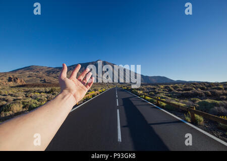 Gerade asphaltierte Straße mit Hand, die auf die Spitze des Pico del Teide Vulkan einladen. Nationalpark Teide, Teneriffa, Kanarische Inseln, Spanien. Stockfoto