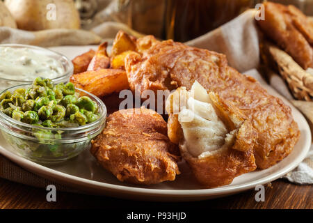 Traditionelle Fisch im Bierteig und Chips mit Erbsen und Sauce Tartar Stockfoto