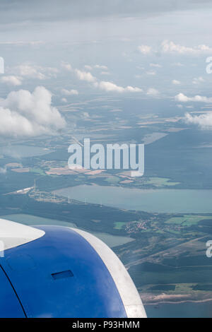 Luftbild vom Flugzeug Fenster auf Jet Engine. Flugzeug über Land mit vielen Feldern und Wolken im Himmel fliegen. Stockfoto