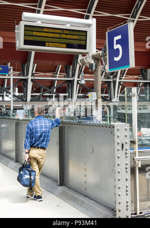 Männliche Beifahrer warten auf einen Zug am Bahnhof Paddington, London, Großbritannien Stockfoto