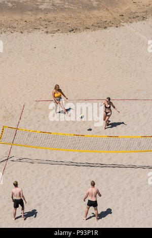 Junge Leute, beim Beachvolleyball am Tolcarne Beach in Newquay in Cornwall. Stockfoto