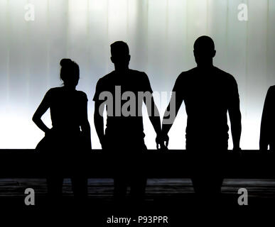 Verschwommene Silhouetten von drei junge Freunde Studenten vor dem modernen Gebäude in der Schwarze und Weiße Nacht Stockfoto