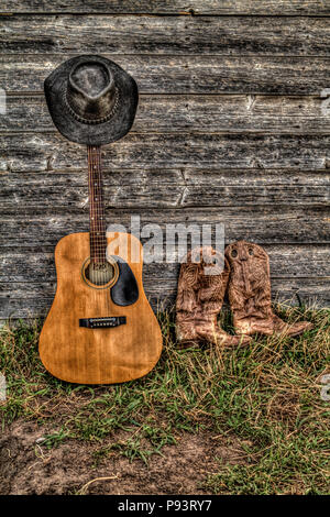 Acoutic Guitar, Cowboy-Hut, Cowboy-Stiefel und alte, Alter Bauernhof Schuppen Wand. Ländlichen Alberta, Kanada. Stockfoto