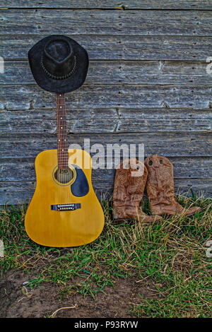 Acoutic Guitar, Cowboy-Hut, Cowboy-Stiefel und alte, Alter Bauernhof Schuppen Wand. Ländlichen Alberta, Kanada. Stockfoto