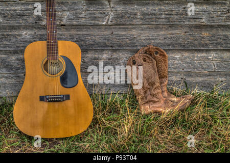 Acoutic Guitar, Cowboy-Hut, Cowboy-Stiefel und alte, Alter Bauernhof Schuppen Wand. Ländlichen Alberta, Kanada. Stockfoto