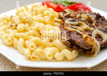 Gekocht auf hausgemachte Nudeln mit gebratenem Schweinefleisch oder Rindfleisch, und weiße Soße, liegen auf einem weißen Teller. Das Konzept der hausgemachten appetitliches Essen. Selektive konzentrieren. Stockfoto