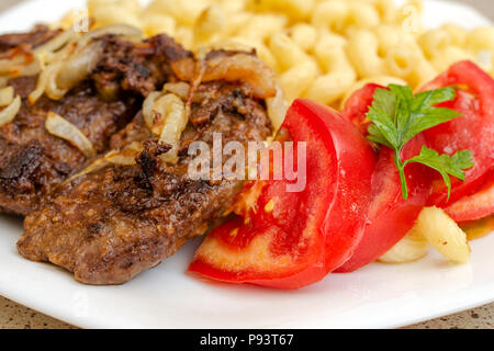 Gekocht auf hausgemachte Nudeln mit gebratenem Schweinefleisch oder Rindfleisch, und weiße Soße, liegen auf einem weißen Teller. Das Konzept der hausgemachten appetitliches Essen. Selektive konzentrieren. Stockfoto