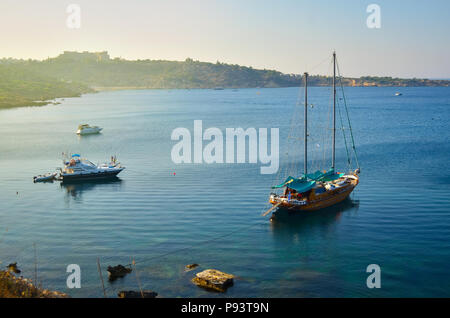 Holz- Yacht und einige Boote sind in einer wunderschönen Bucht an einem Sonnenuntergang verankert. Konnos Bay, Zypern. Stockfoto