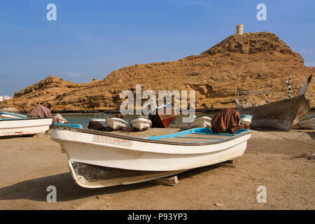 OMAN, Ash Sharqiyah Region, Sur, Boote am Strand mit Turm von Al Ayajh Fort an der Rückseite Stockfoto