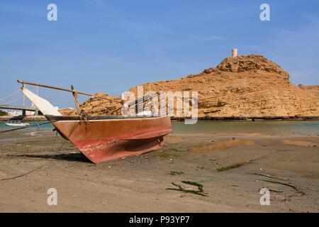 OMAN, Ash Sharqiyah Region, Sur, Boote am Strand mit Turm von Al Ayajh Fort an der Rückseite Stockfoto