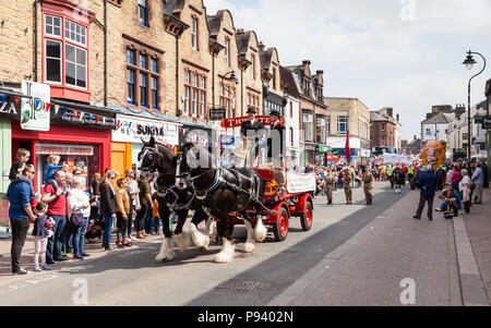 Zwei Shire pferde ziehen eine Thwaites dray Wagen im Mai Day Parade in der Innenstadt Penrith, England. Thwaites ist eine historische Brauerei im Jahre 1807 gegründet. Stockfoto